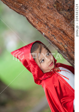 Sweet girl wearing a Little red riding hood costume. Real family having fun while using costumes of the Little red riding hood tale in Halloween. Sweet girl wearing a Little red riding hood costume. Real family having fun while using costumes of the Little red riding hood tale in Halloween. 104381524