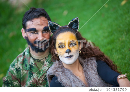 Young couple wearing wolf and woodcutter costumes. Real family having fun while using costumes of the Little red riding hood tale in Halloween. Young couple wearing wolf and woodcutter costumes. Real family having fun while using costumes of the Little red riding hood tale in Halloween. 104381799