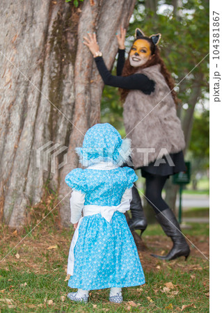 Little girl on grandma costume playing with her mom. Real family having fun while using costumes of the Little red riding hood tale in Halloween. Little girl on grandma costume playing with her mom. Real family having fun while using costumes of the Little red riding hood tale in Halloween. 104381867