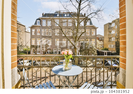 a balcony with two chairs and a table in front of an open window looking out onto the canal from outside 104381952