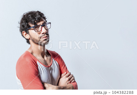 Portrait of young man with crossed arms isolated. Young latin man in glasses with crossed arms looking in profile at the camera. Nicaraguan man with crossed arms looking at the camera isolated Portrait of young man with crossed arms isolated. Young latin man in glasses with crossed arms looking in profile at the camera. Nicaraguan man with crossed arms looking at the camera isolated 104382288