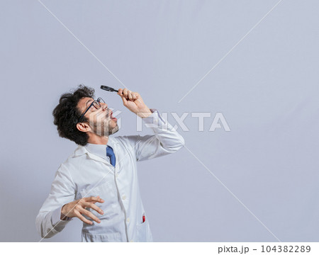 Surprised man in lab coat with magnifying glass looking at an advertisement above. Scientist man looking up with a magnifying glass. Amazed man observing an advertisement with a magnifying glass Surprised man in lab coat with magnifying glass looking at an advertisement above. Scientist man looking up with a magnifying glass. Amazed man observing an advertisement with a magnifying glass 104382289