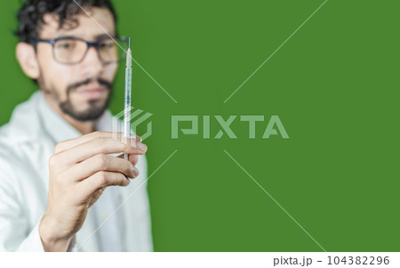 Close-up of a doctor's hand holding a syringe, Close-up of a hand holding an injection on an isolated background, Doctor and syringe concept Close-up of a doctor's hand holding a syringe, Close-up of a hand holding an injection on an isolated background, Doctor and syringe concept 104382296