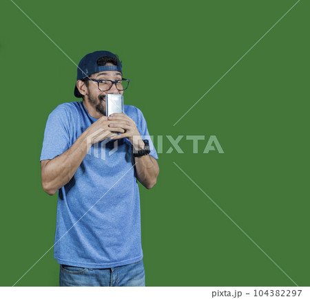 boy in glasses smiling with his cell phone, young man in cap smiling while holding his cell phone on white background, boy smiling covering his mouth with cell phone boy in glasses smiling with his cell phone, young man in cap smiling while holding his cell phone on white background, boy smiling covering his mouth with cell phone 104382297