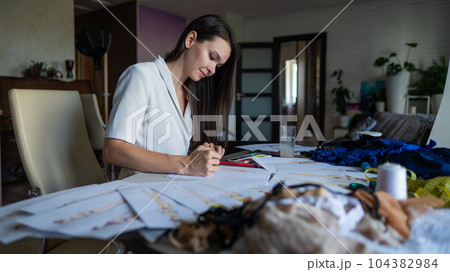 A woman draws sketches of swimwear and underwear with a pencil. 104382984
