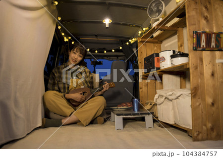 夜のオートキャンプ場で車の中で寛ぐ若い女性　車中泊イメージ 104384757