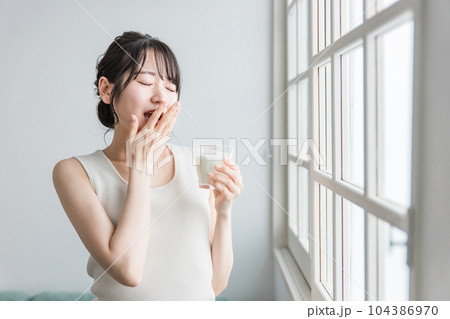 ミルク・牛乳を飲むあくびをする眠いアジア人女性 ミルク・牛乳を飲むあくびをする眠いアジア人女性 104386970