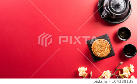 Chinese Mid-Autumn Festival concept made from mooncakes, tea and plum blossom on red background. 104388138