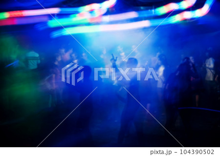 blurred silhouettes of people at concert at event with bright multicoloured light effects blurred silhouettes of people at concert at event with bright multicoloured light effects 104390502