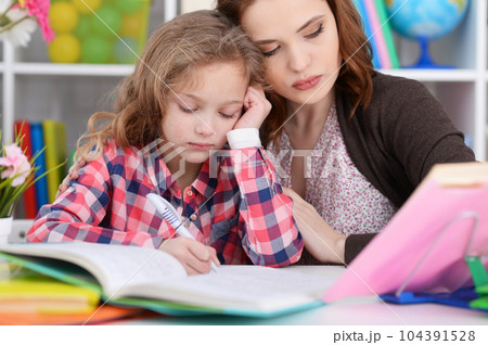 Cute little girl with her mother doing homework Cute little girl with her mother doing homework 104391528