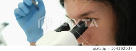 Laboratory diagnostics doctor looking into microscope and making blood test in clinic 104392037