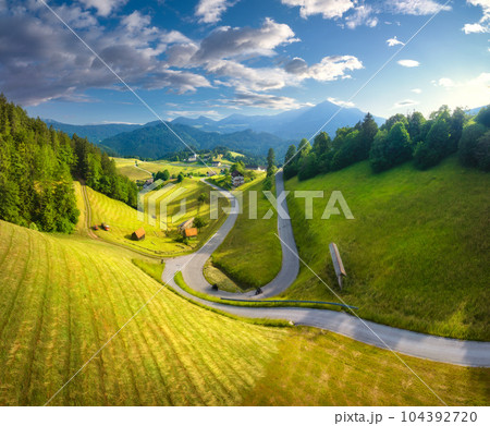 Aerial view of country road in green meadows at sunset in summer Aerial view of country road in green meadows at sunset in summer 104392720