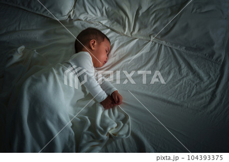 infant baby sleeping on bed at night 104393375