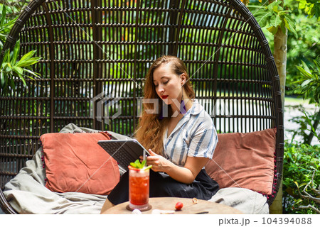 Beautiful blonde woman artist and illustrator thinking about a concept of her drawing, sitting by the table with electronical tablet and stylus Beautiful blonde woman artist and illustrator thinking about a concept of her drawing, sitting by the table with electronical tablet and stylus 104394088