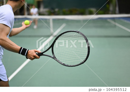 Tennis player serving tennis ball during a match on open court. Sport, fitness, training and active life concept Tennis player serving tennis ball during a match on open court. Sport, fitness, training and active life concept 104395512