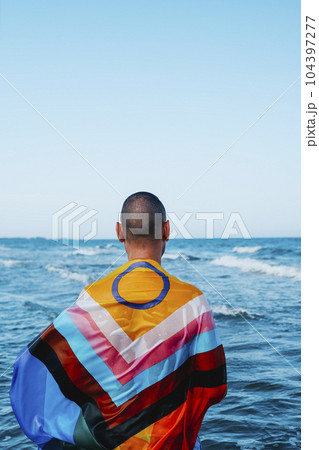 man wrapped in a progress pride flag in the ocean man wrapped in a progress pride flag in the ocean 104397277