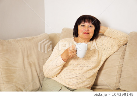 Happy relaxed senior woman in good mood drinking a cup of coffee or hot tea at home. 104399149