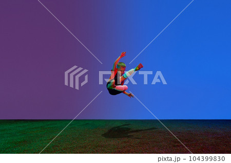Male beginner soccer player in sports uniform in action, motion with ball over dark blue background in neon. Concept of sport, health, action, ad 104399830