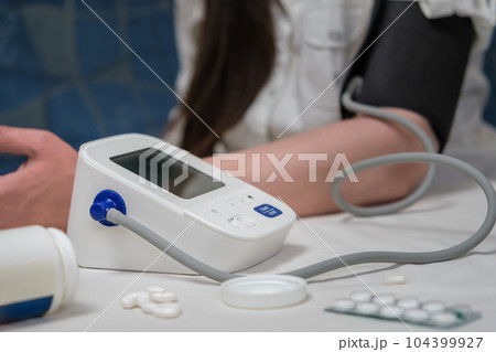 woman using modern blood pressure monitor at home. woman measuring blood pressure during self-examination 104399927