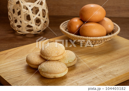 High angle view pile of small homemade sweet cake filled with pineapple jam on wooden board. High angle view pile of small homemade sweet cake filled with pineapple jam on wooden board. 104403182