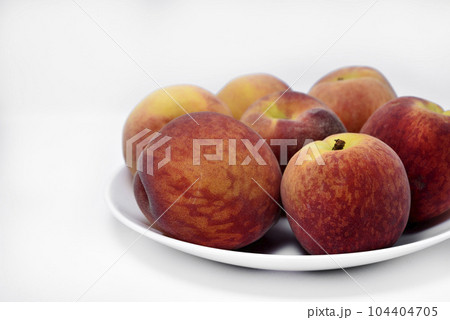Juicy peaches on a white plate. Yellow-red large ripe peaches. Juicy fruits. 104404705