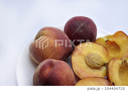 Juicy peaches on a white plate. Yellow-red large ripe peaches. Juicy fruits. 104404720