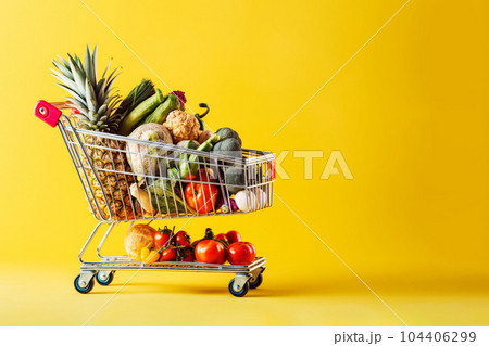 Food price inflation. Shopping cart full of groceries on yellow background. Copy space. Food price inflation. Shopping cart full of groceries on yellow background. Copy space. 104406299