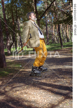 Funny old man on roller skates and walking stick. 104406496