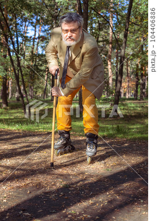 Funny old man on roller skates and walking stick. 104406886