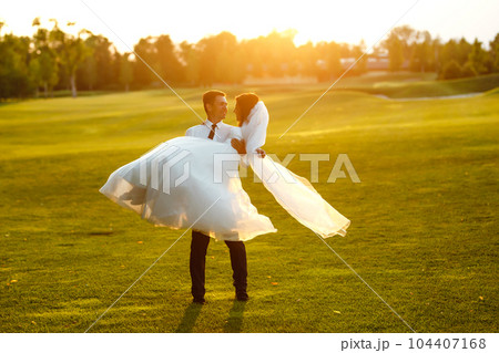 Groom circling bride in beautiful white dress at sunset. Lovely wedding couple at sunset. Together. 104407168