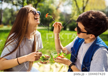 friends enjoying a healthy meal. Boy and girl eating healthy food. Healthy lifestyle. Concept picnic. friends enjoying a healthy meal. Boy and girl eating healthy food. Healthy lifestyle. Concept picnic. 104407420