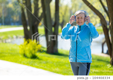 Woman in blue blazer in headphones in the park Woman in blue blazer in headphones in the park 104408334