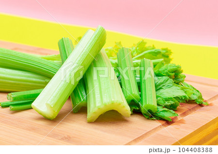 Fresh Celery Stem and Chopped Celery Sticks on Wooden Cutting Board 104408388