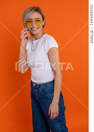 Satisfied woman in white t shirt and jeans talking on mobile phone 104408505