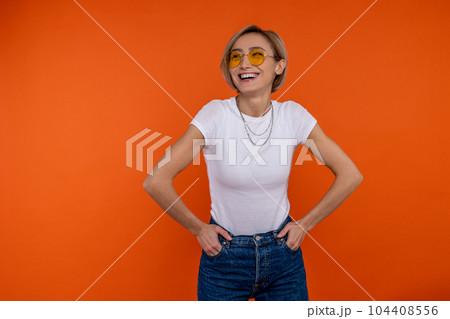 Happy laughing woman in white t shirt and jeans standing with hands on hips Happy laughing woman in white t shirt and jeans standing with hands on hips 104408556