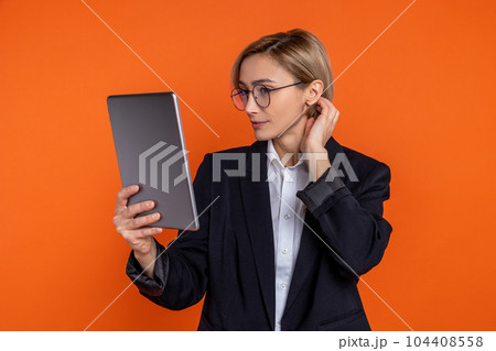 Attractive woman wearing black official style suit standing with tablet Attractive woman wearing black official style suit standing with tablet 104408558