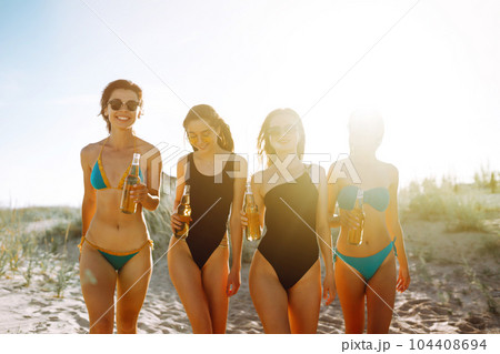 Happy Four girls dancing and drinking beers on the beach at sunset. Summer holidays, vacation. Happy Four girls dancing and drinking beers on the beach at sunset. Summer holidays, vacation. 104408694