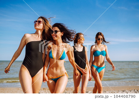 Happy four girls strolling along a beach. Young women enjoying on beach holiday. Summer, relax. 104408790