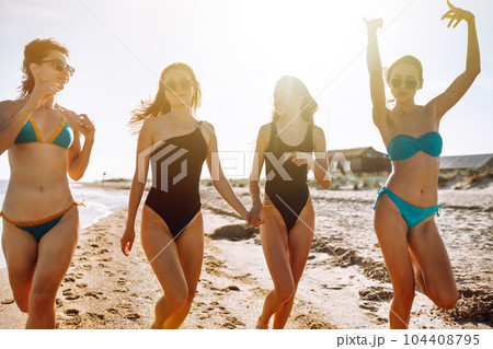 Four young girls having fun on the beach. Group of girlfriends enjoying on beach holiday. Summer lifestyle. 104408795