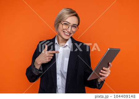 Happy woman wearing black official style suit pointing at tablet 104409148