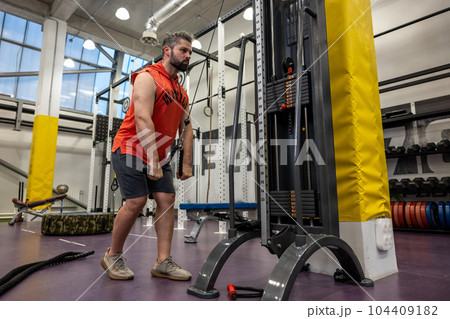 Man working out at gym, doing cable rope pushdowns, biceps and triceps arm training workout. Man working out at gym, doing cable rope pushdowns, biceps and triceps arm training workout. 104409182