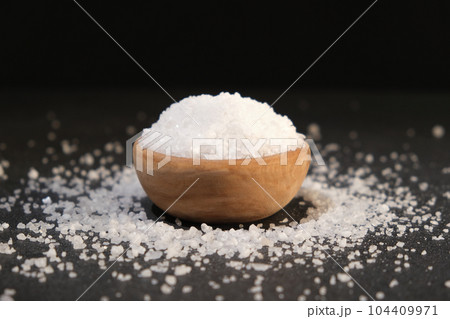 salt into a wooden spoon from a bowl on a black salt into a wooden spoon from a bowl on a black 104409971