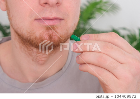 A young man takes out a tablet, a pill from a A young man takes out a tablet, a pill from a 104409972