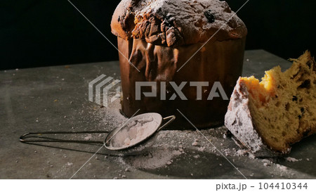 Christmas baking in Italy. Delicious festive bread with powdered sugar. View on black background. Christmas baking in Italy. Delicious festive bread with powdered sugar. View on black background. 104410344