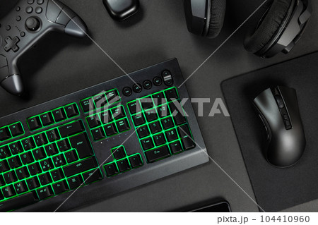 Green lit keyboard surrounded by various modern wireless gadgets 104410960