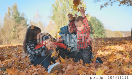 A happy family in an autumn park having fun and crumbling leaves. 104411111