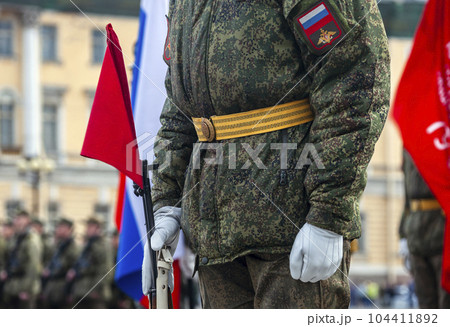 Field military uniform of Russian soldier at parade rehearsal against the background of the colors of the national flag. 104411892