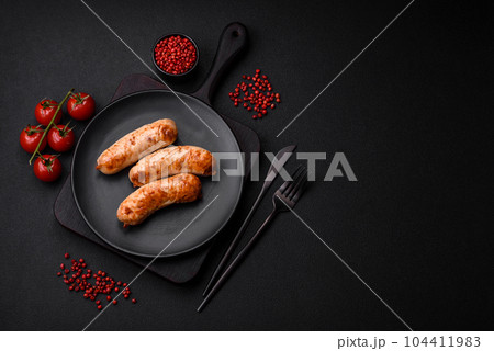 Delicious juicy grilled sausages with salt, spices and herbs on a ceramic plate Delicious juicy grilled sausages with salt, spices and herbs on a ceramic plate 104411983