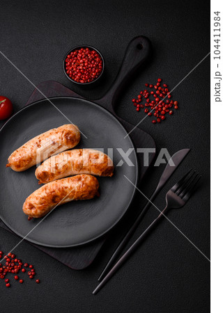 Delicious juicy grilled sausages with salt, spices and herbs on a ceramic plate Delicious juicy grilled sausages with salt, spices and herbs on a ceramic plate 104411984