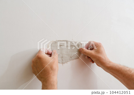 A handyman is repairing a hole in the drywall in the wall. 104412051